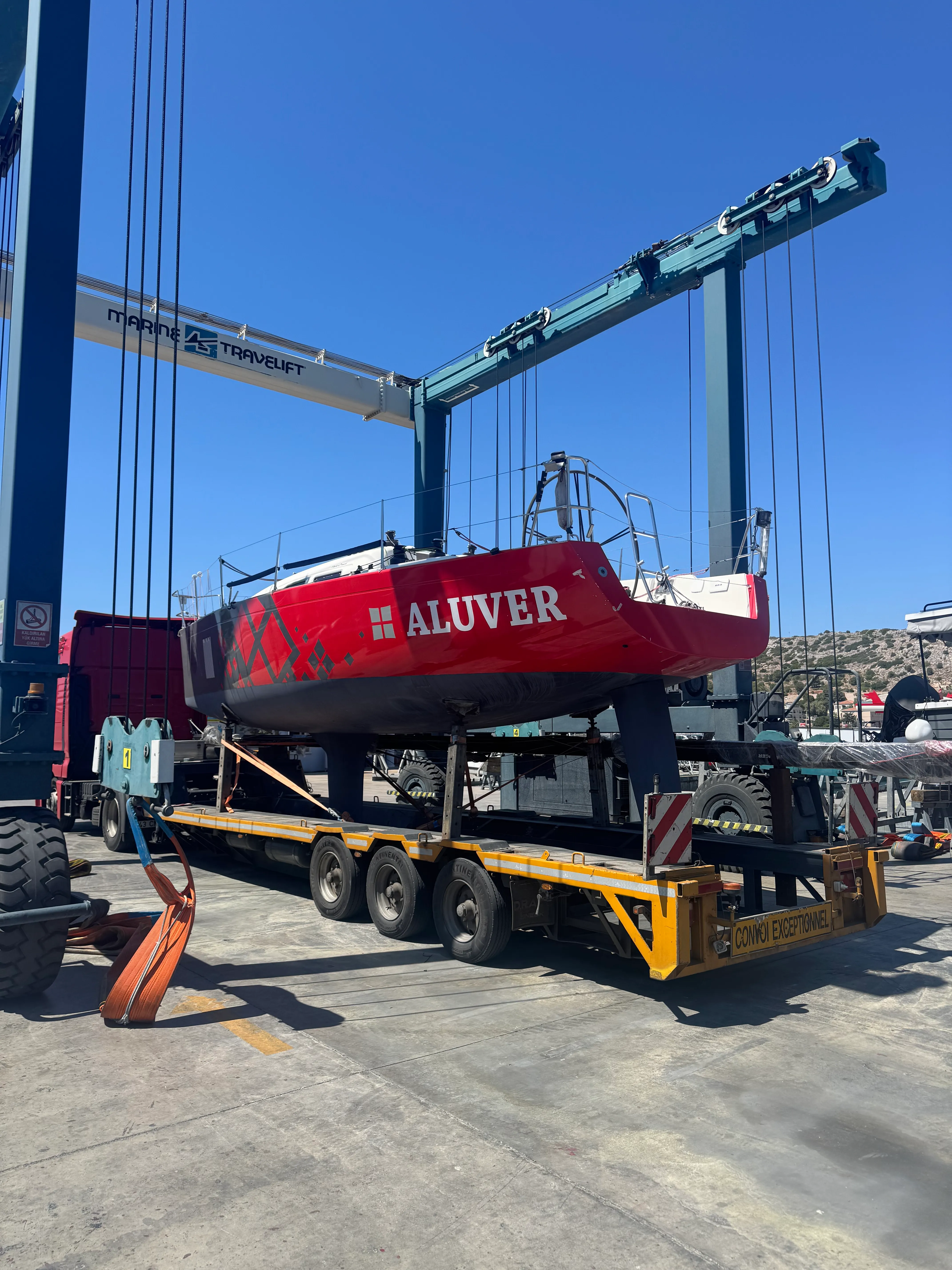 Red Aluver boat being lifted by a yellow handler.
