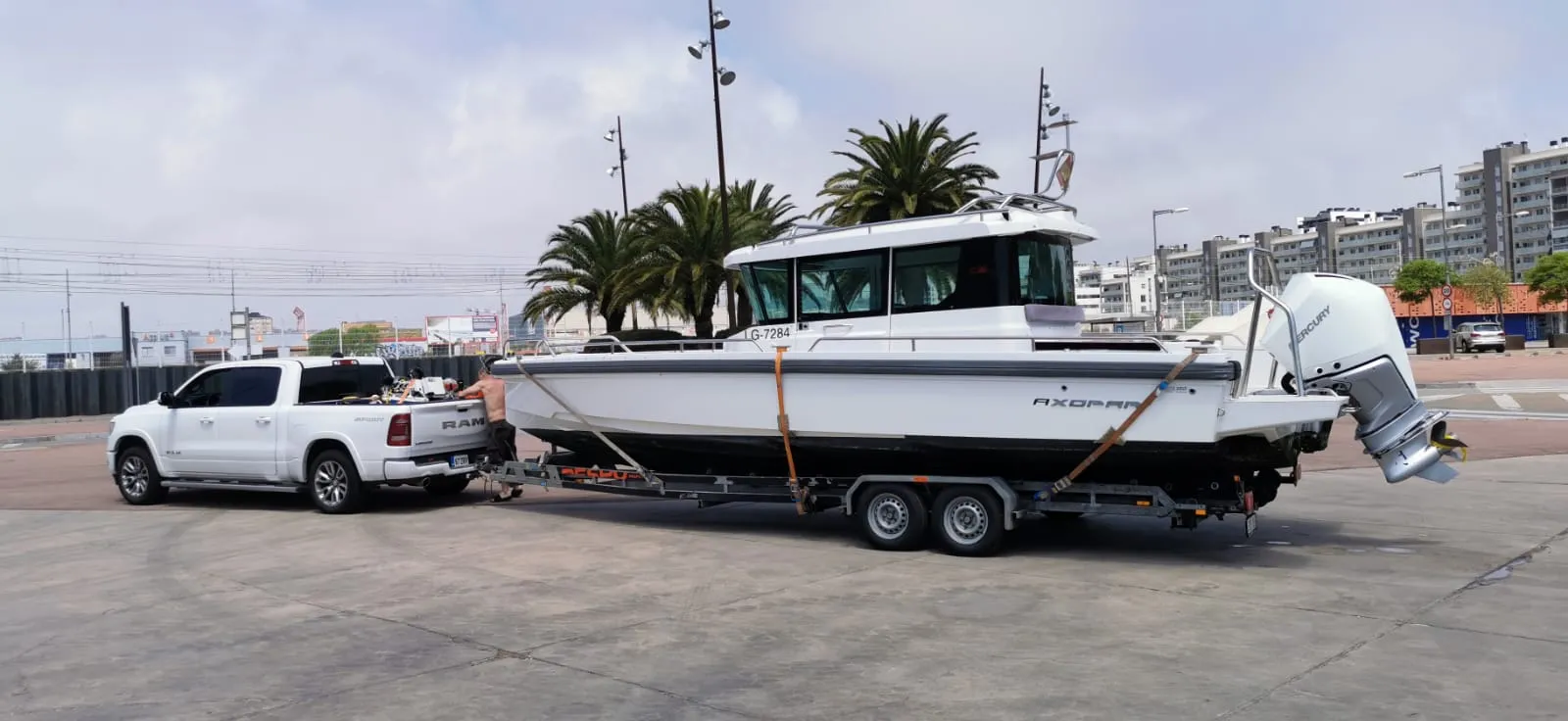 Axopar boat being towed by a Ram pickup in a Spanish coastal city.