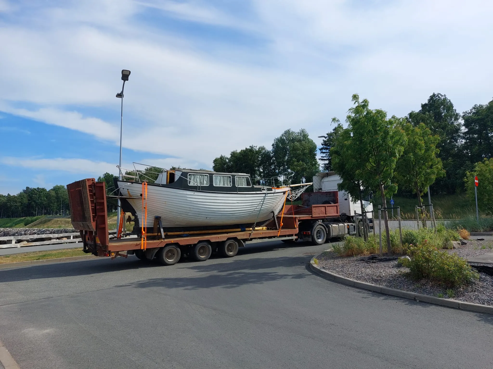 Classic motorboat on a low-loader passing through a roundabout.
