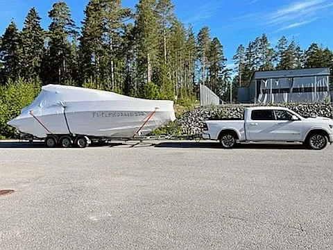 Shrink-wrapped boat being delivered through a Finnish forest.