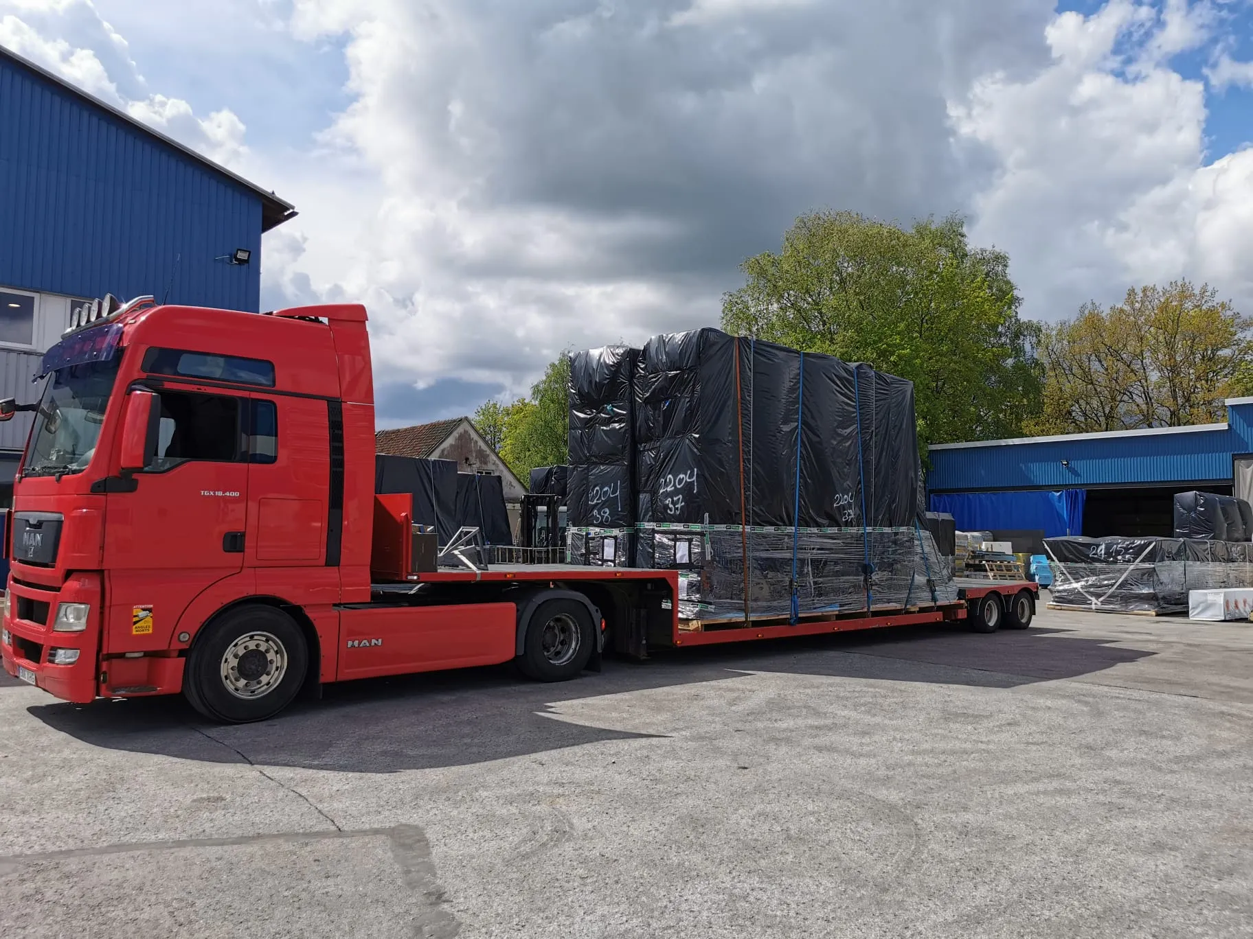 Palletized industrial cargo on a low-loader trailer.