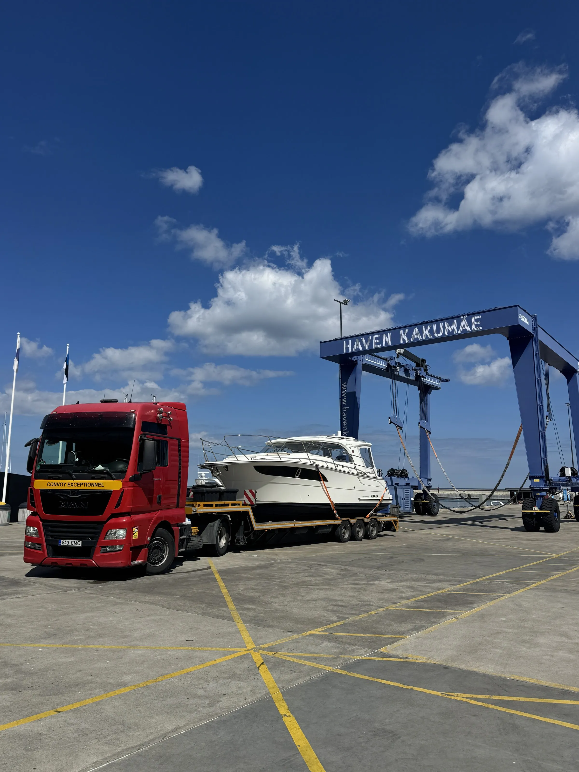 Red MAN truck with a white Marex cruiser on a yellow low-loader under the Haven Kakumäe boat lift.