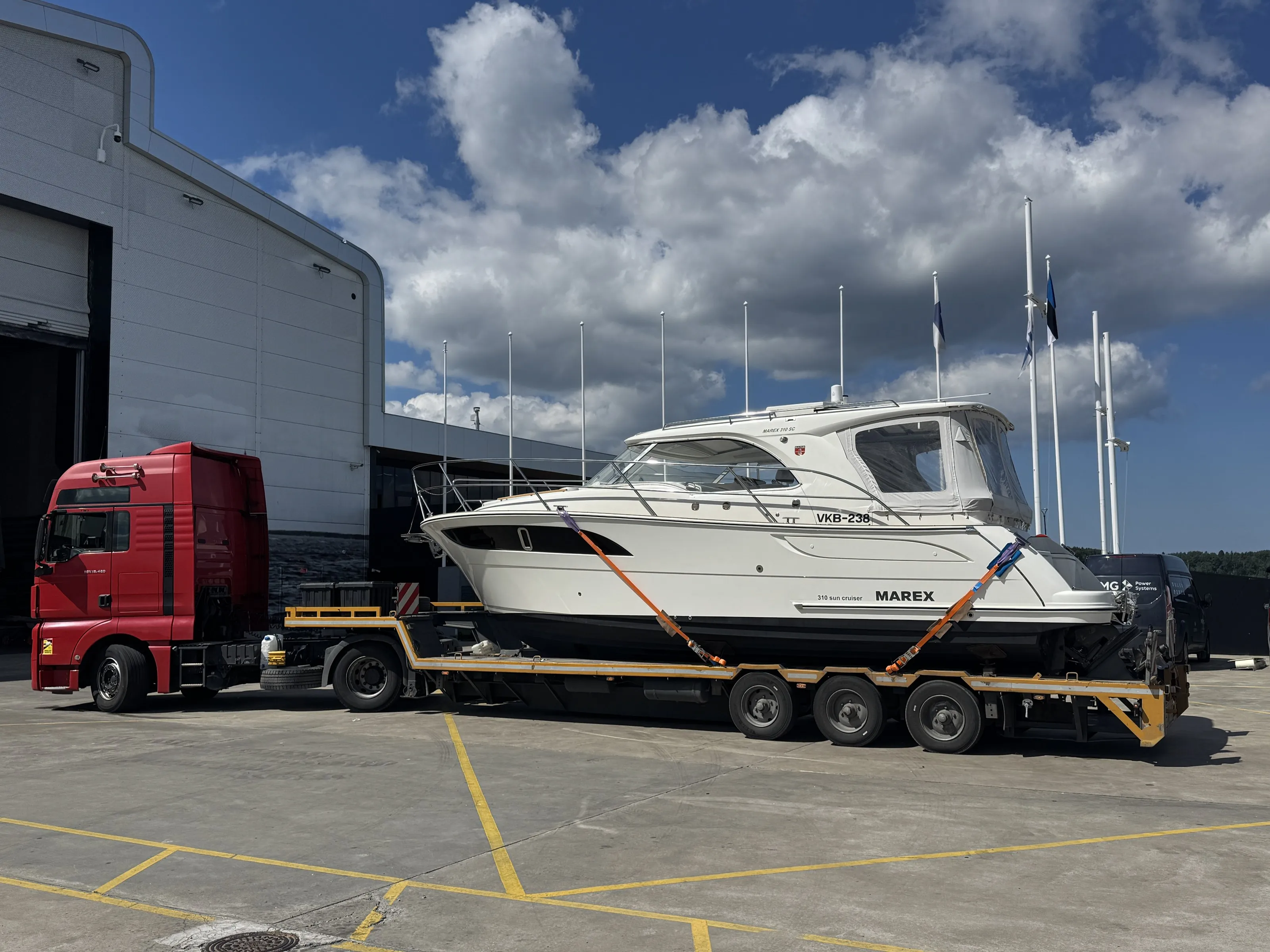 White Marex 310 Sun Cruiser secured on a yellow low-loader trailer.