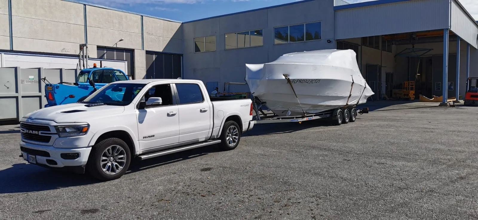 Ram pickup with shrink-wrapped boat at an Italian boatyard.