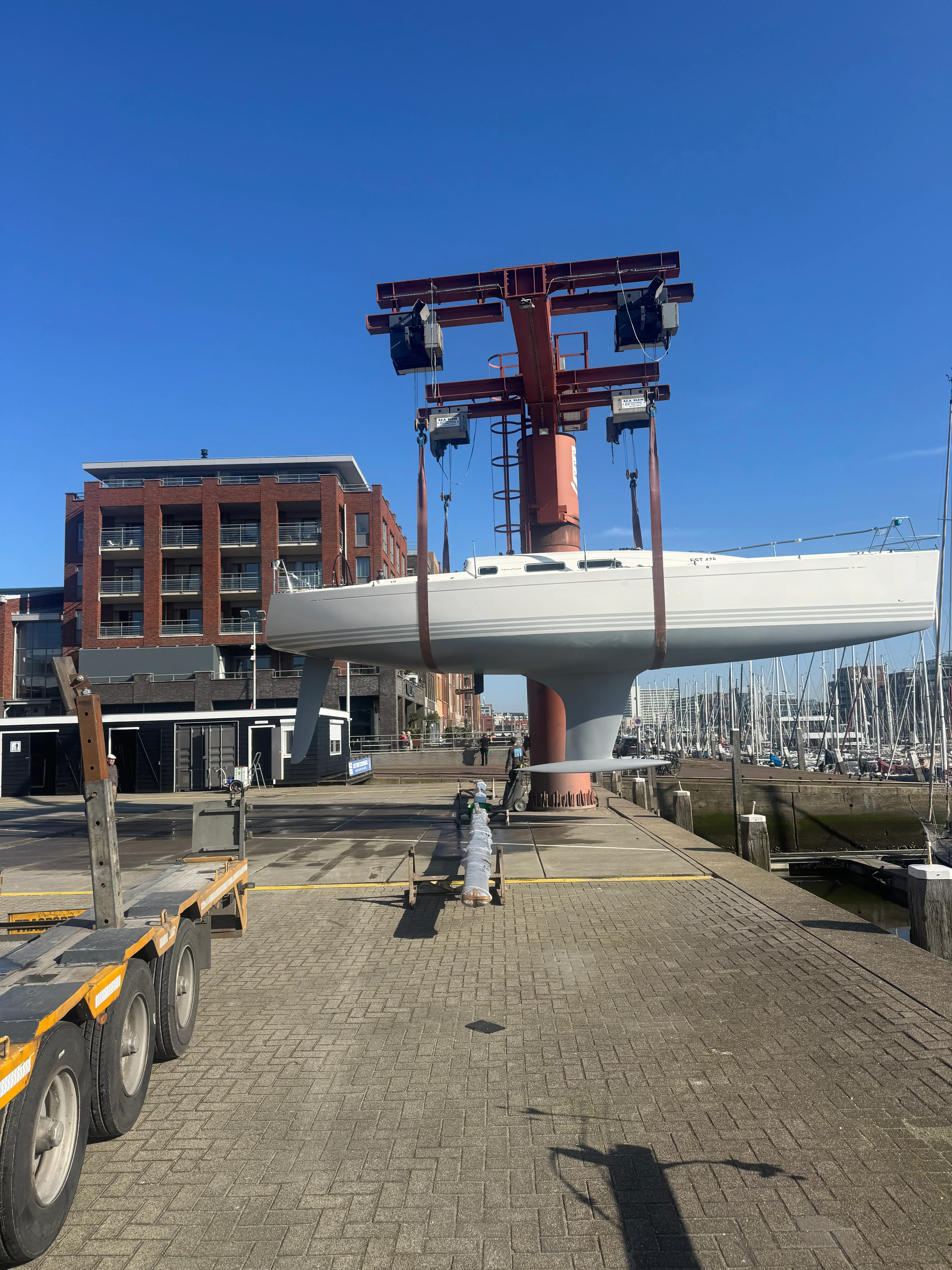 Large yacht being lifted at a brick boatyard.
